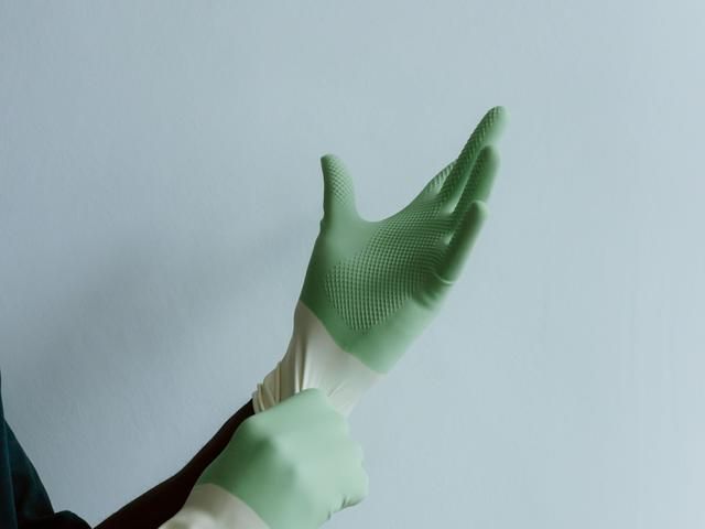 Cleaner pulling on green gloves