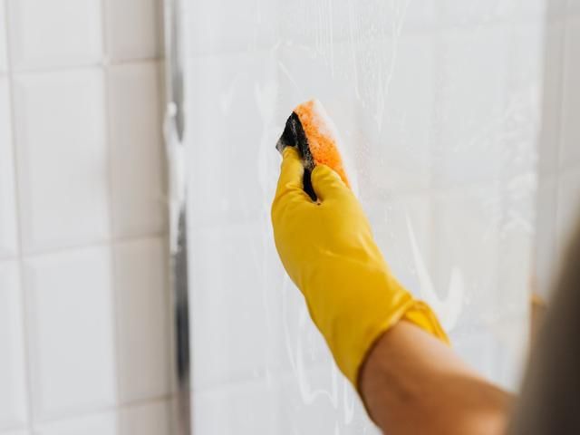 Gloved hand scrubbing glass with foam